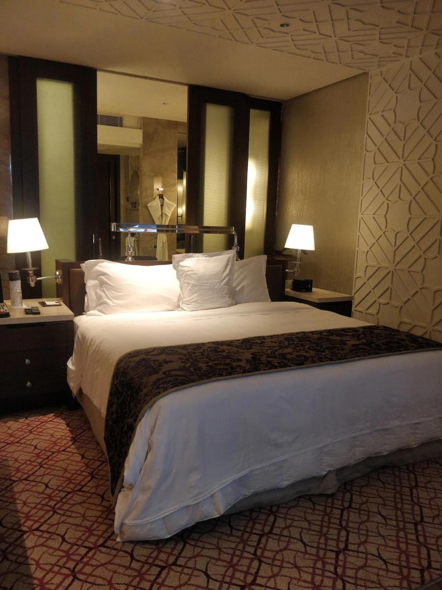a large bed in a hotel room with two lamps at ITC Kohenur, a Luxury Collection Hotel, Hyderabad in Hyderabad