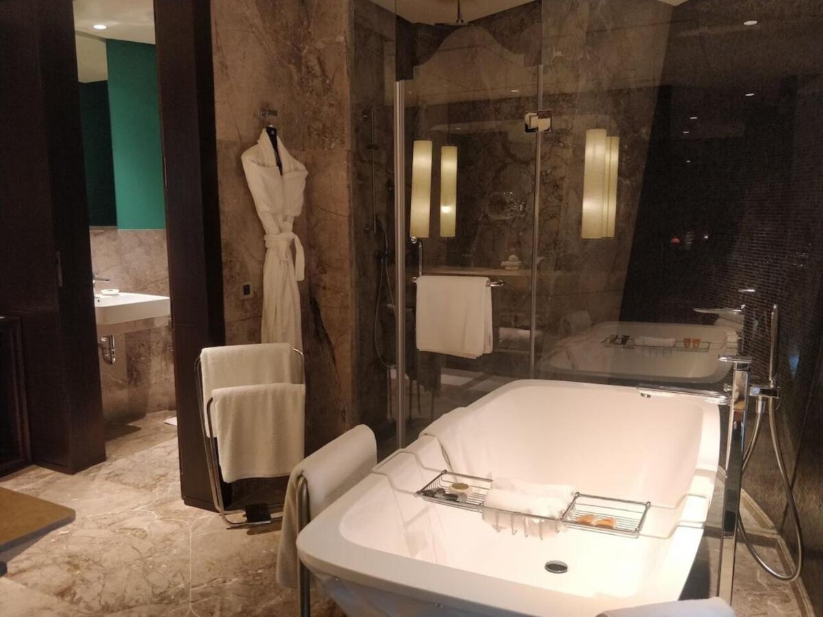 a bathroom with a bath tub and a dress hanging on a wall at ITC Kohenur, a Luxury Collection Hotel, Hyderabad in Hyderabad