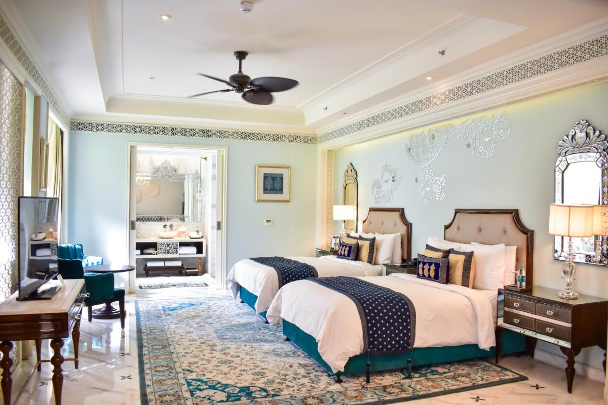 a large bedroom with two beds and a television at The Leela Palace Jaipur in Jaipur