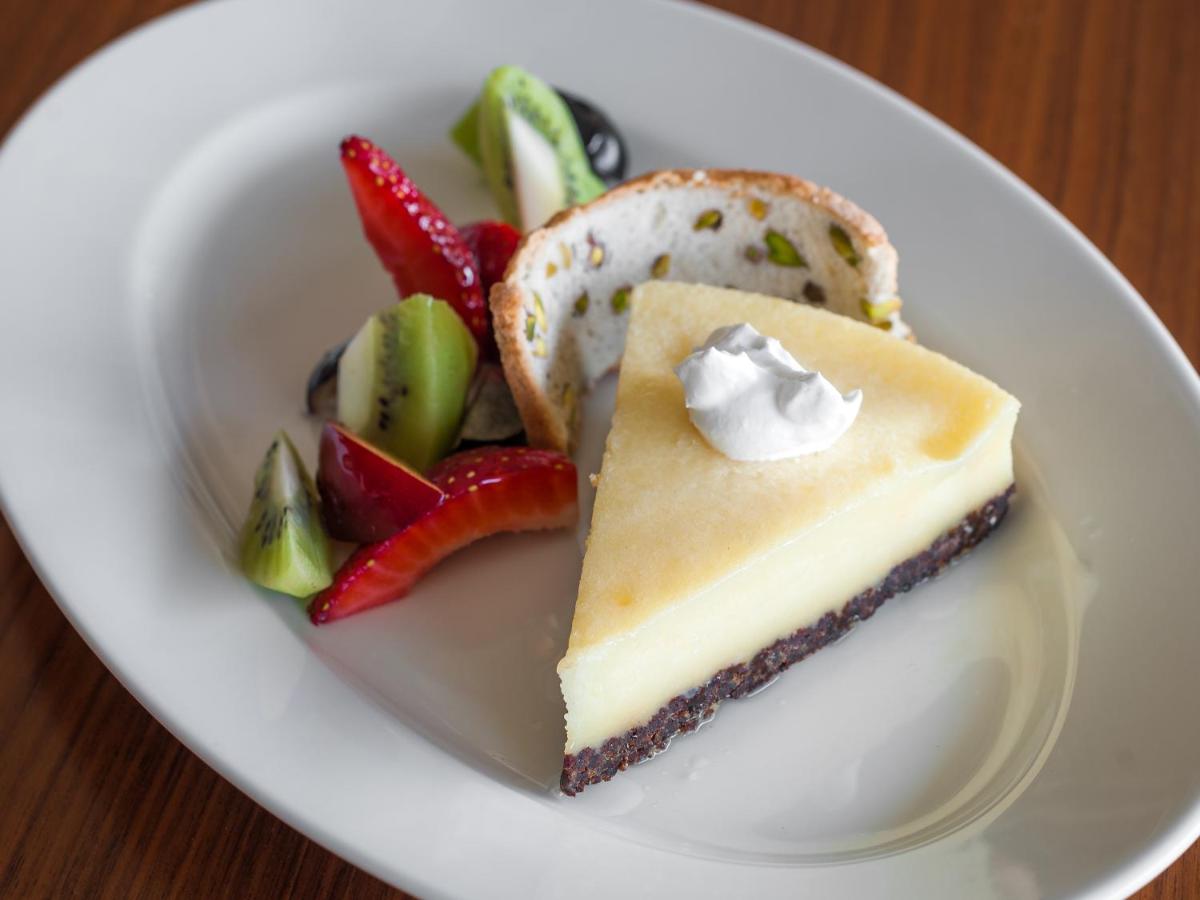 a white plate with a piece of cheesecake and strawberries at Hyatt Place Pune Hinjawadi in Pune