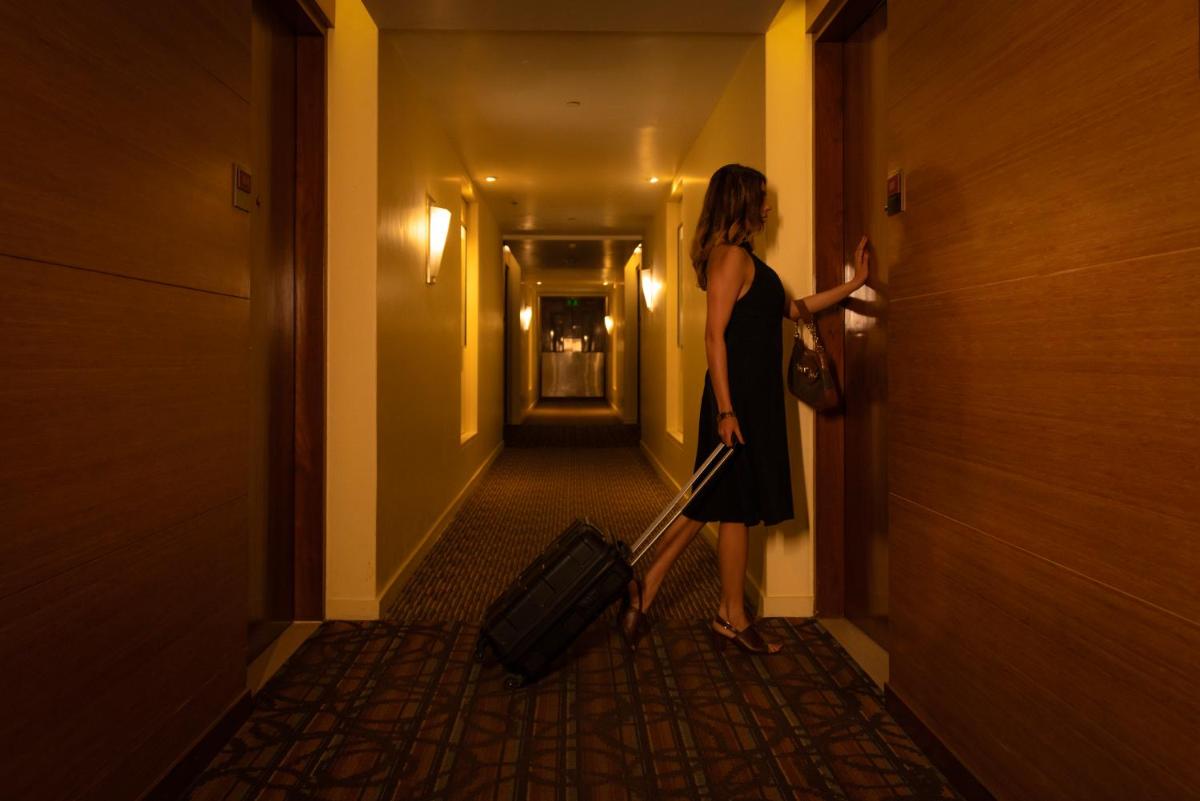 a woman in a black dress pulling a suitcase down a hallway at Hyatt Place Pune Hinjawadi in Pune