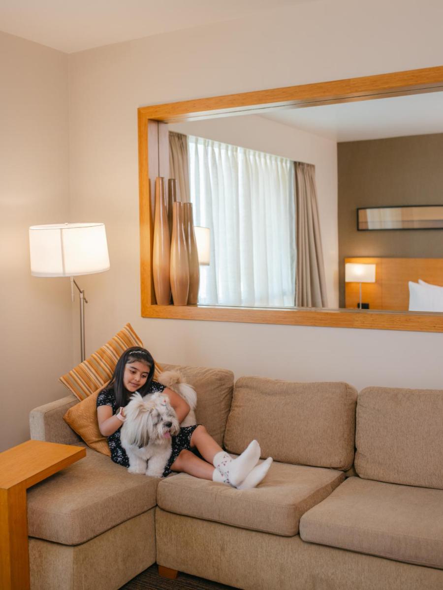a woman sitting on a couch with a dog at Hyatt Place Pune Hinjawadi in Pune