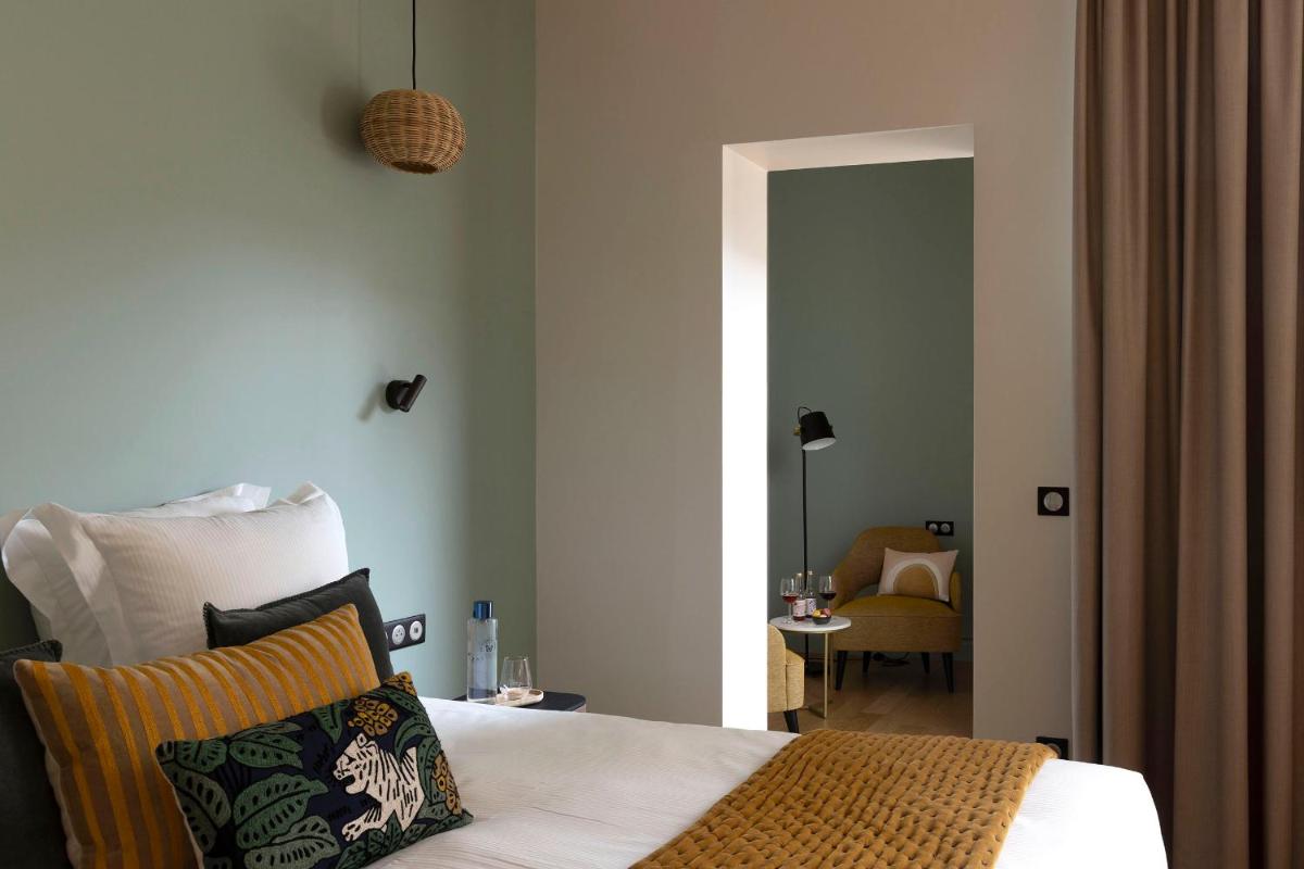 une chambre avec un lit et une pièce avec une chaise dans l'établissement L'INVITATION AU VOYAGE - Hôtel & Spa, à Honfleur