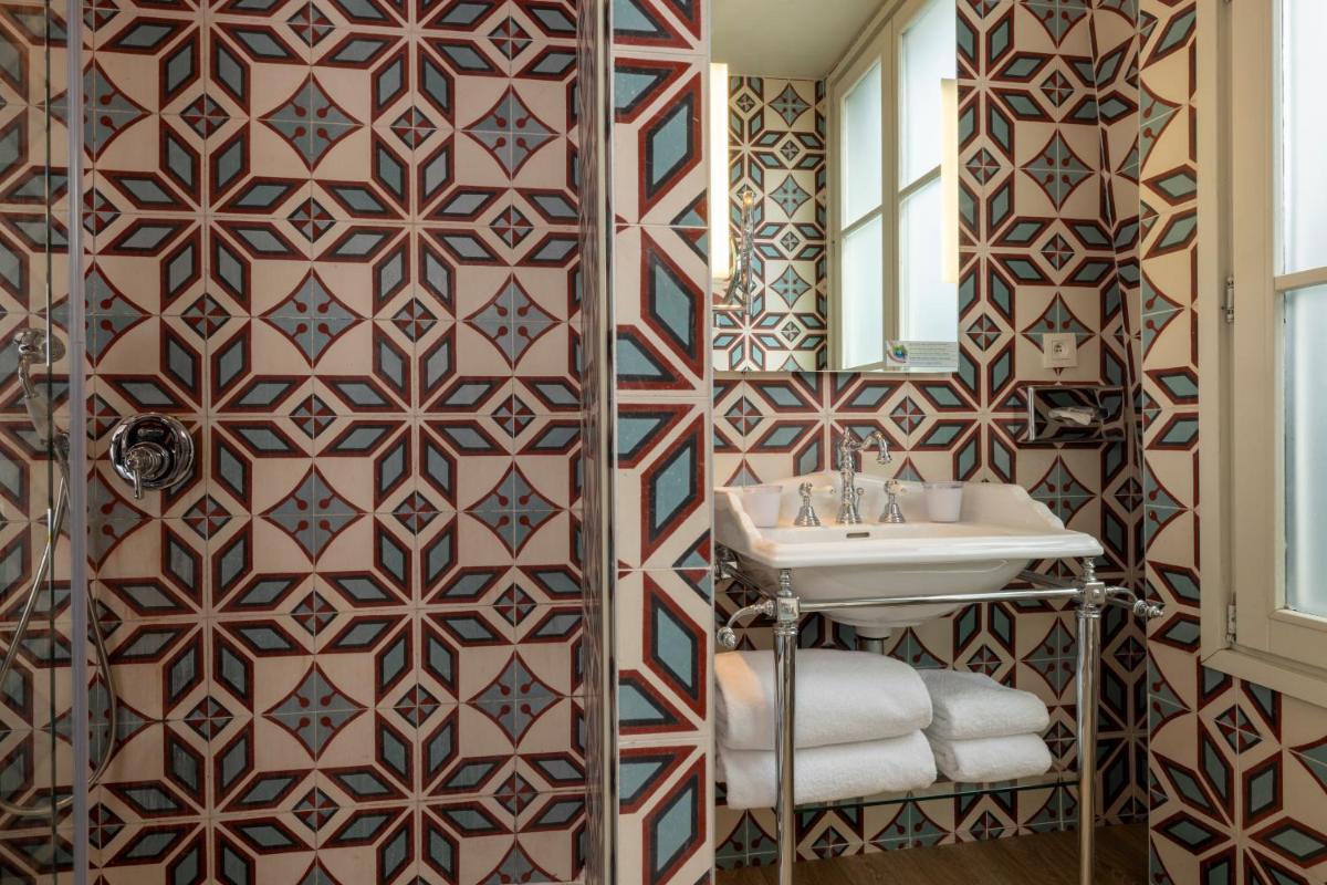 La salle de bains est pourvue d'un lavabo et d'un mur recouvert de carrelage. dans l'établissement Hotel L’Antoine, à Paris 101 autres photos