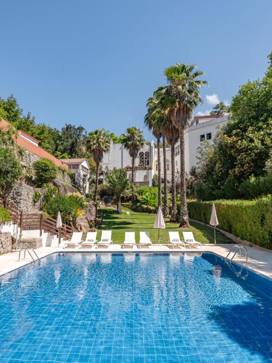 uma piscina com cadeiras e palmeiras em Villa Termal Spa Hotel - Villa Termal Spa Resort - by Unlock Hotels em Monchique