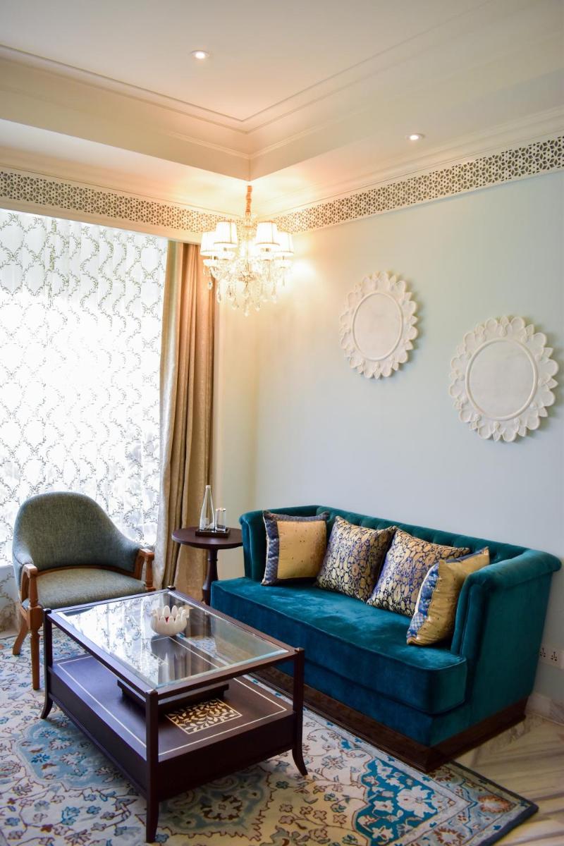 a living room with a blue couch and a coffee table at The Leela Palace Jaipur in Jaipur