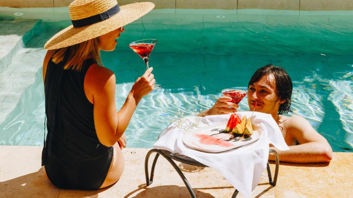 deux femmes assises à une table avec un verre dans une piscine dans l'établissement Hôtel Liberata & Spa, à LʼÎle-Rousse 68 autres photos
