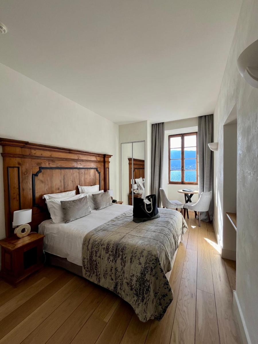 une chambre avec un grand lit à tête de lit en bois dans l'établissement Abbaye de Talloires, à Talloires 31 autres photos