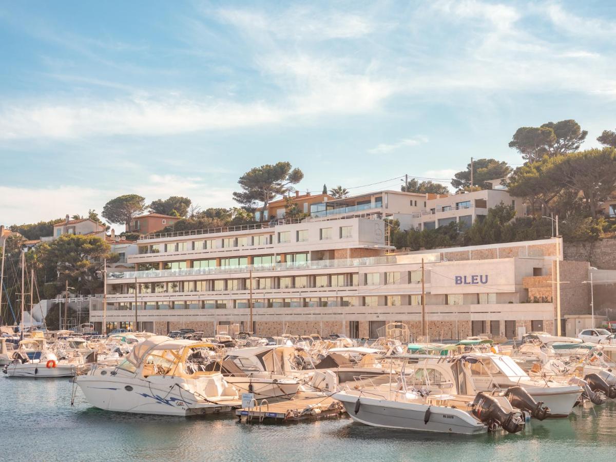 un groupe de bateaux amarrés dans une marina avec un bâtiment dans l'établissement Bleu Hôtel & Spa, à Carry-le-Rouet