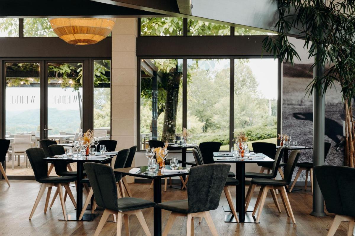 une salle à manger avec tables, chaises et fenêtres dans l'établissement Domaine de Rochebois & Spa Nuxe, à Sarlat-la-Canéda