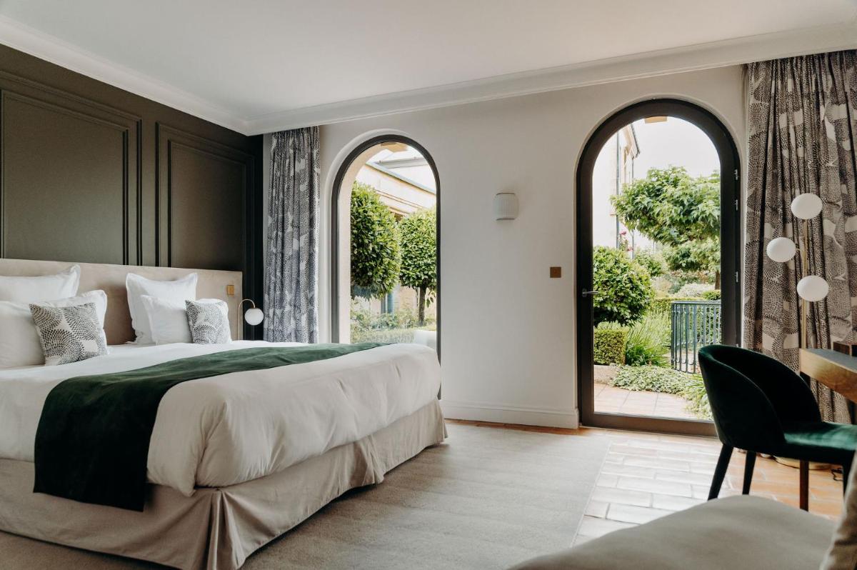 une chambre avec un grand lit et une grande fenêtre dans l'établissement Domaine de Rochebois & Spa Nuxe, à Sarlat-la-Canéda