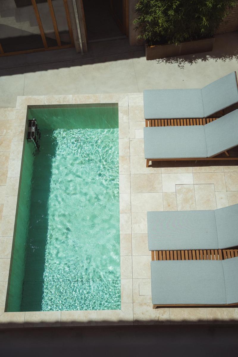 - une vue sur la piscine et ses 2 bancs dans l'établissement La Maison Gaïa Hôtel & Spa, à Torreilles