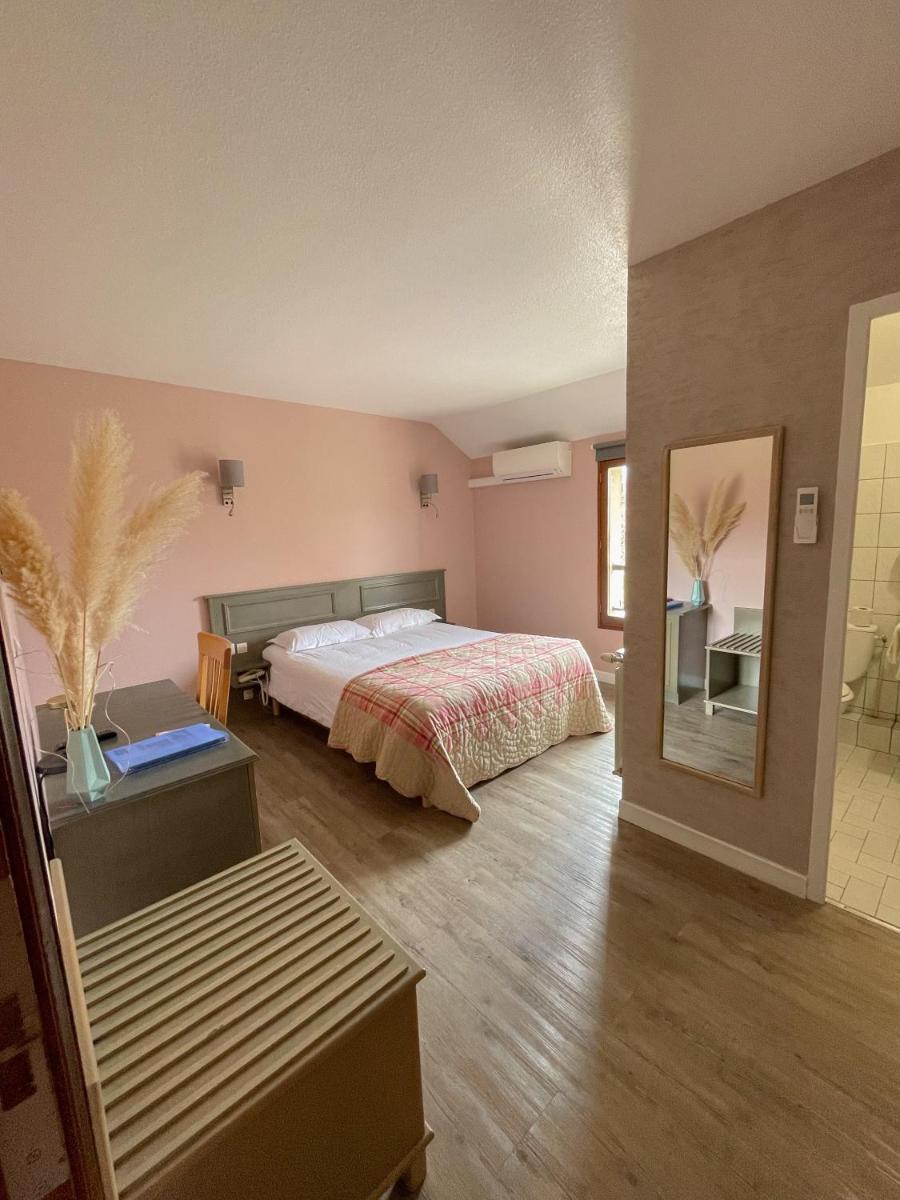 une chambre avec un lit et un miroir dans l'établissement Maison Legate "Hôtel Le Baudiere & Spa", à Saint-Beauzire