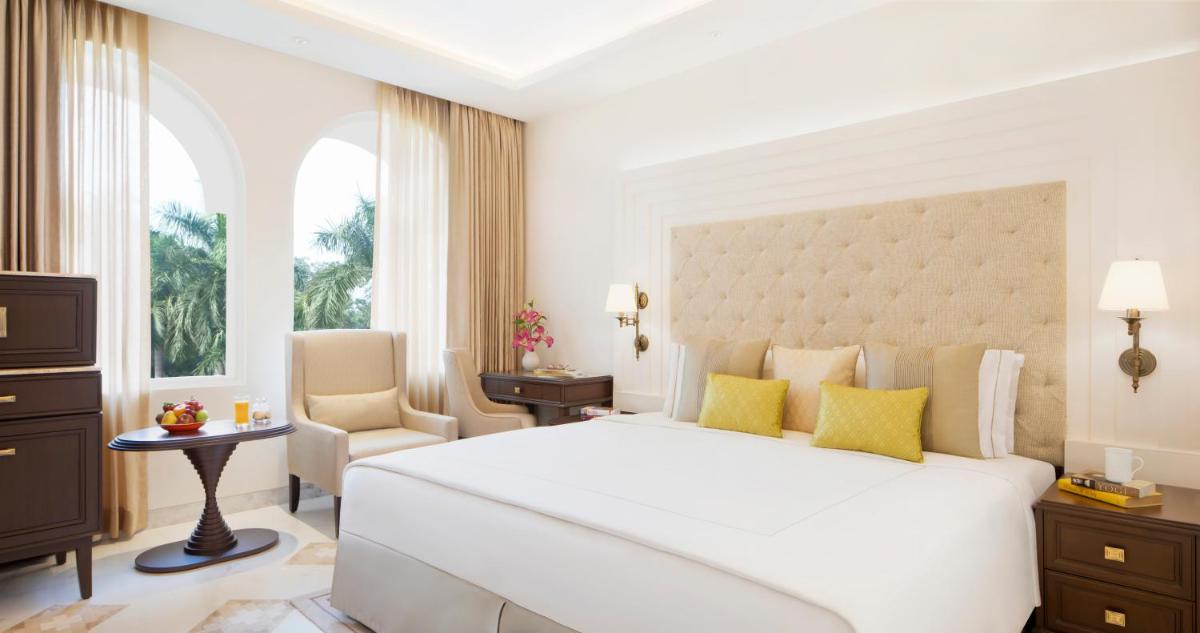 a white bedroom with a large bed and a chair at Taj Ganges Varanasi in Varanasi
