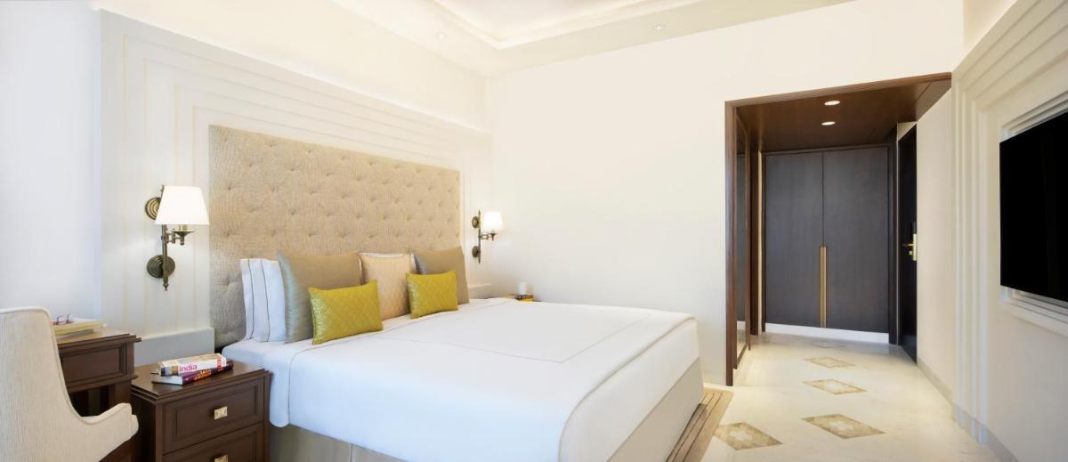 a white bedroom with a large white bed with yellow pillows at Taj Ganges Varanasi in Varanasi
