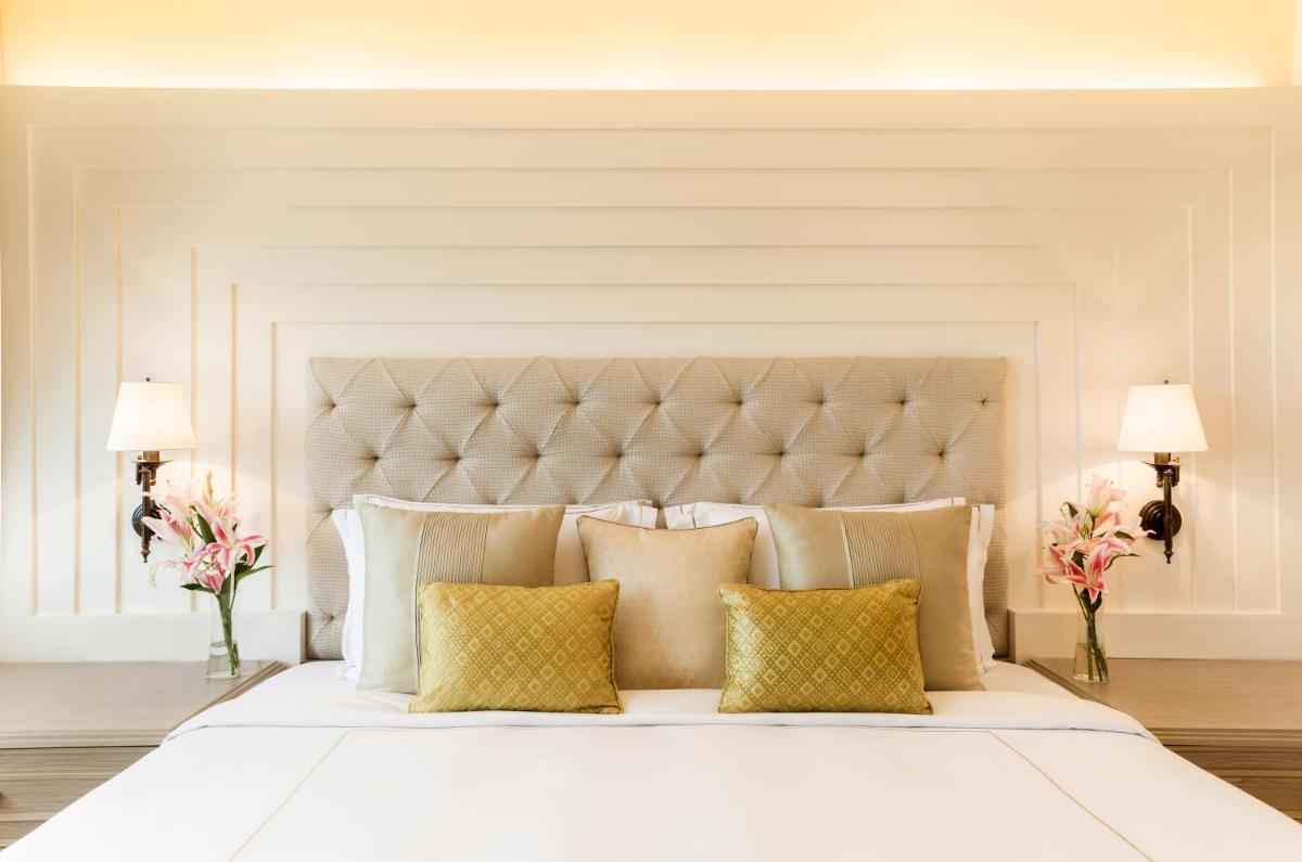 a bedroom with a large white bed with yellow pillows at Taj Ganges Varanasi in Varanasi