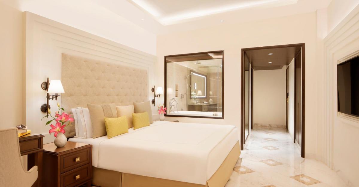 a bedroom with a large white bed and a mirror at Taj Ganges Varanasi in Varanasi