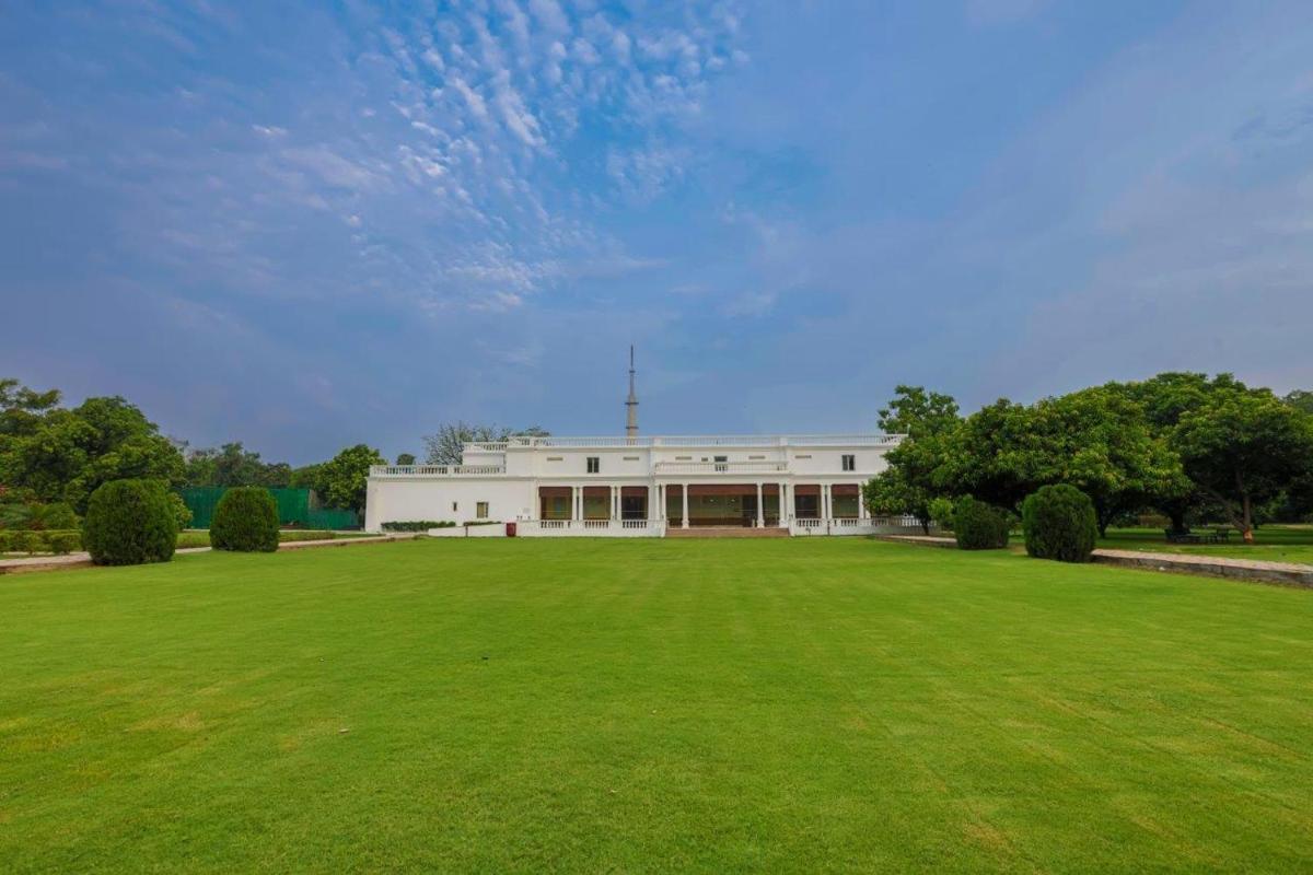 a large white building with a large grass field at Taj Ganges Varanasi in Varanasi