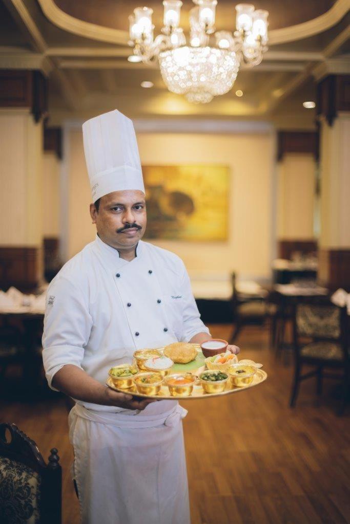 a chef is holding a plate of food at Taj Ganges Varanasi in Varanasi