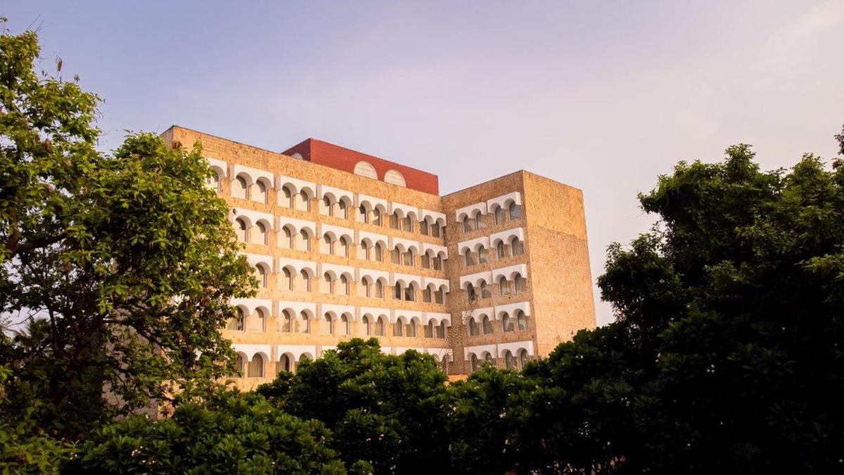 a large brick building with trees in front of it at Taj Ganges Varanasi in Varanasi