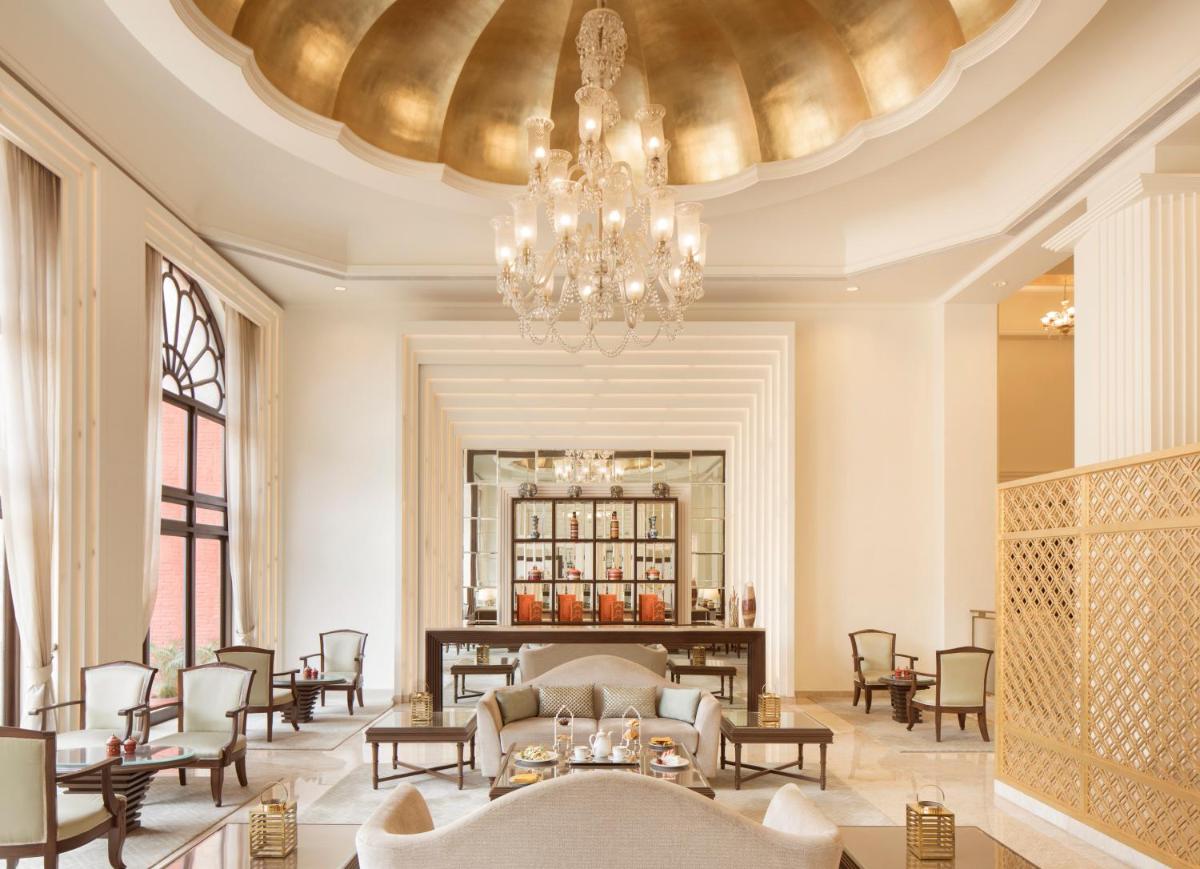 a lobby with a chandelier and tables and chairs at Taj Ganges Varanasi in Varanasi