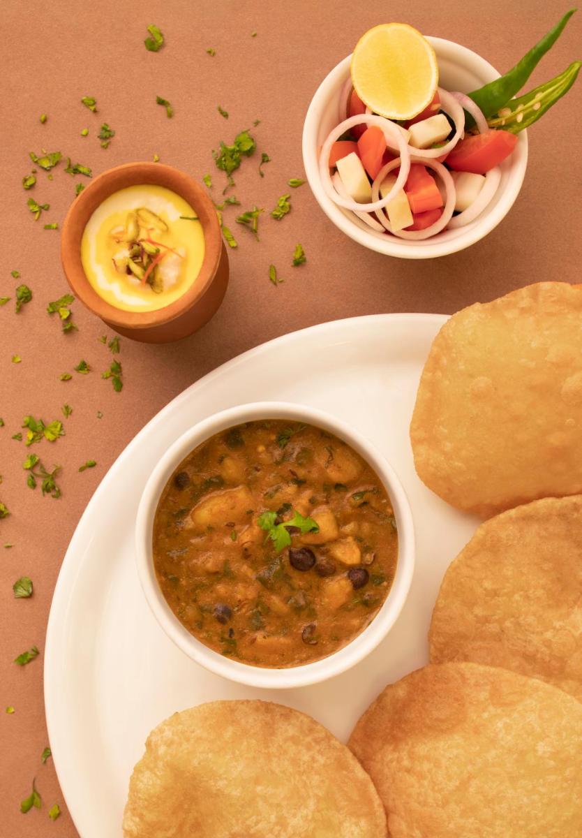 a plate of food with a bowl of soup and bread at Taj Ganges Varanasi in Varanasi