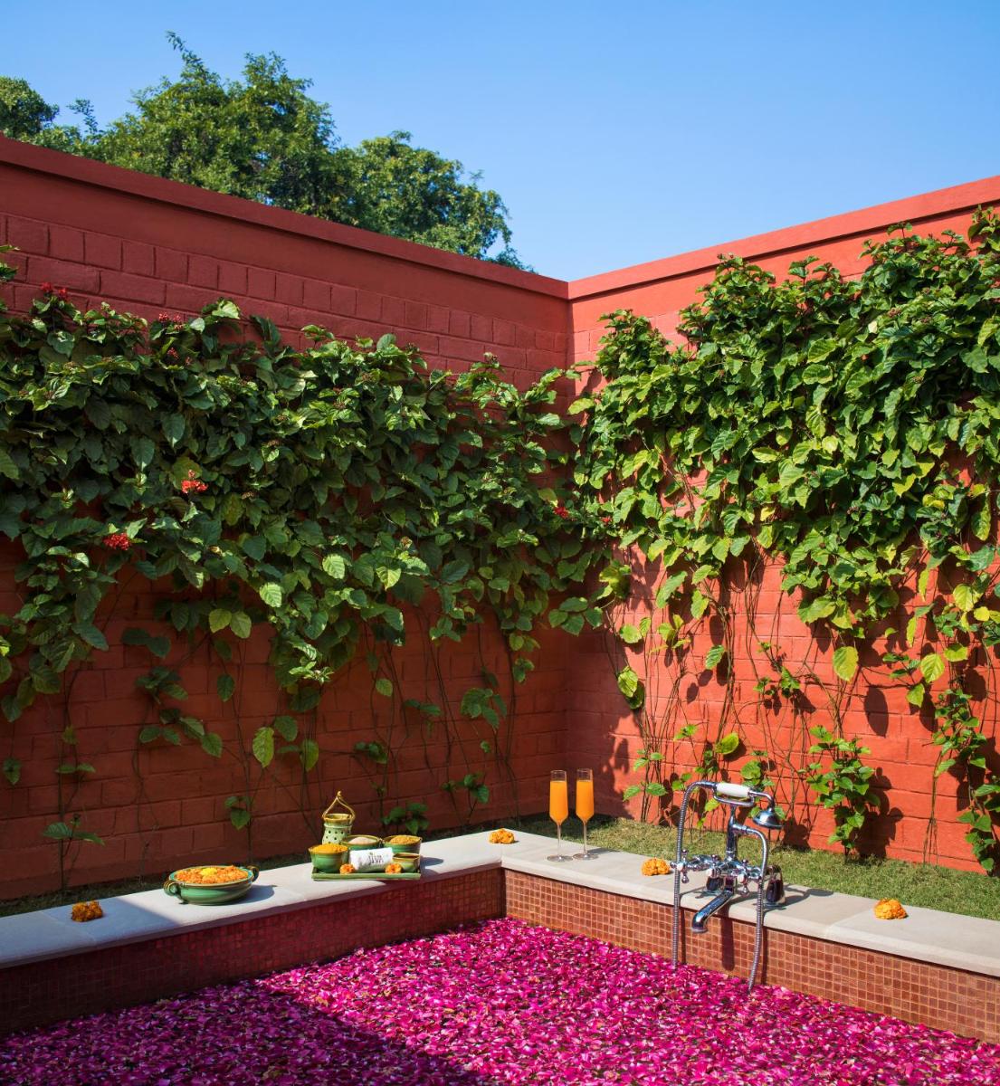 a garden with pink flowers on a brick wall at Taj Ganges Varanasi in Varanasi