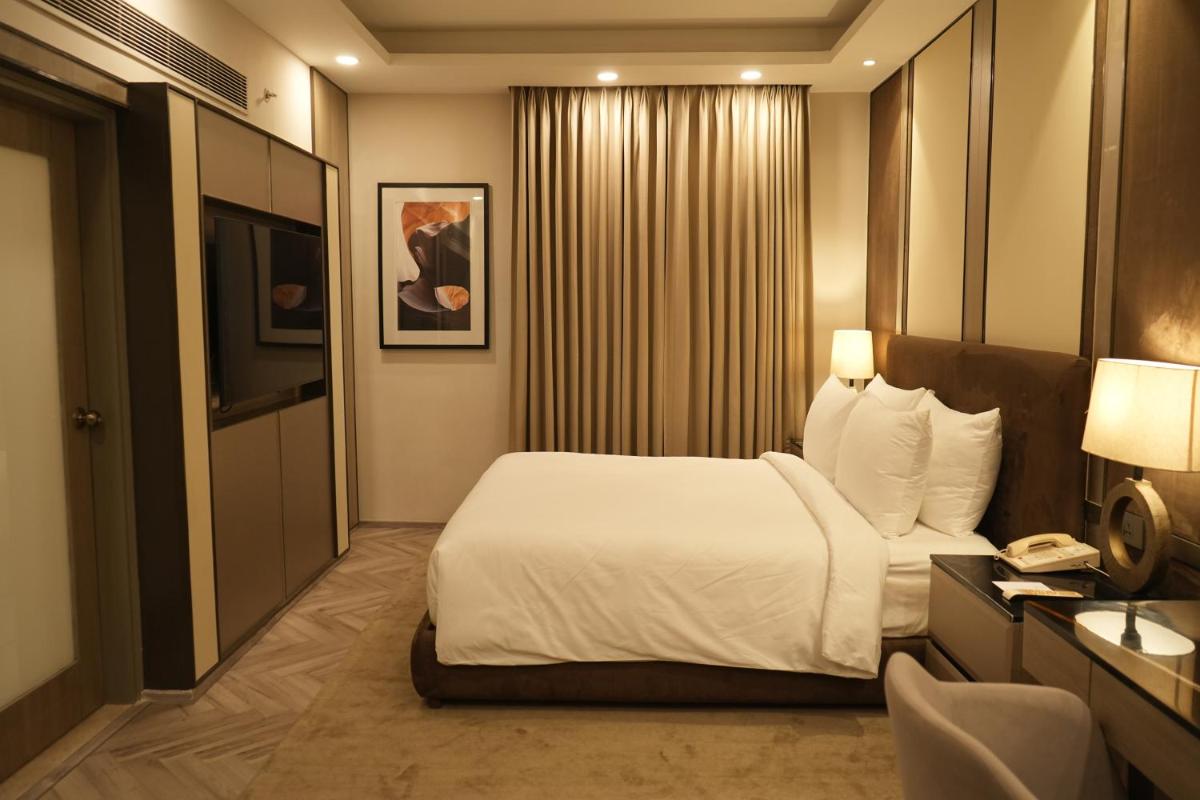 a hotel room with a bed and a phone at The Suryaa New Delhi in New Delhi a hotel room with a bed and a phone at The Suryaa New Delhi in New Delhi