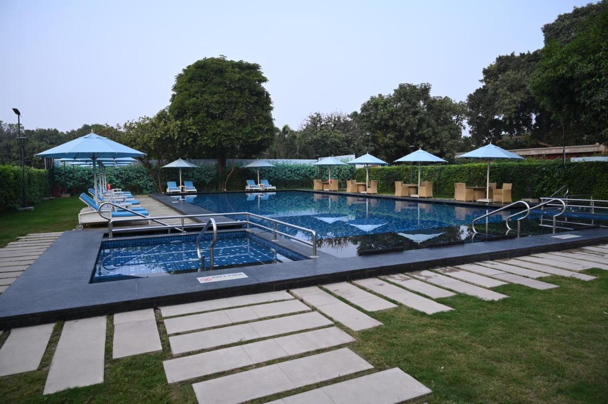 a large swimming pool with chairs and umbrellas at Taj Ganges Varanasi in Varanasi
