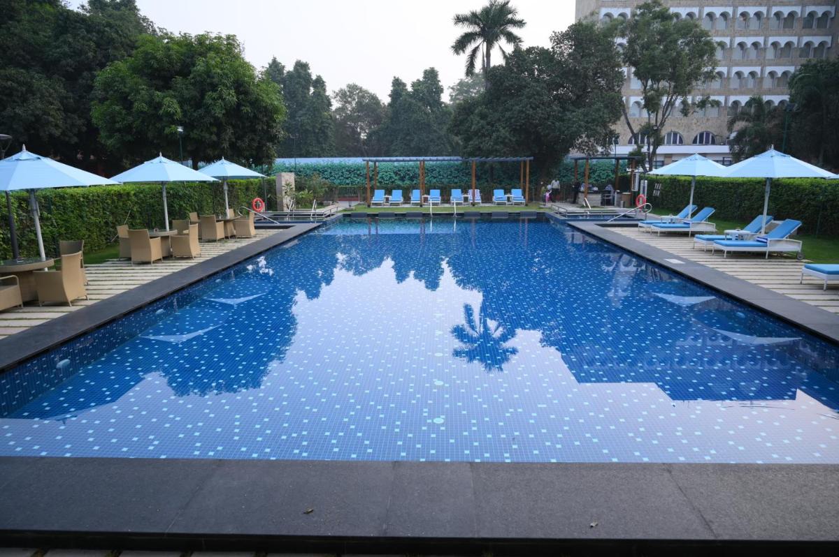 a large swimming pool with chairs and umbrellas at Taj Ganges Varanasi in Varanasi