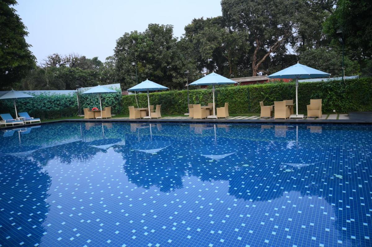 a swimming pool with chairs and umbrellas at Taj Ganges Varanasi in Varanasi