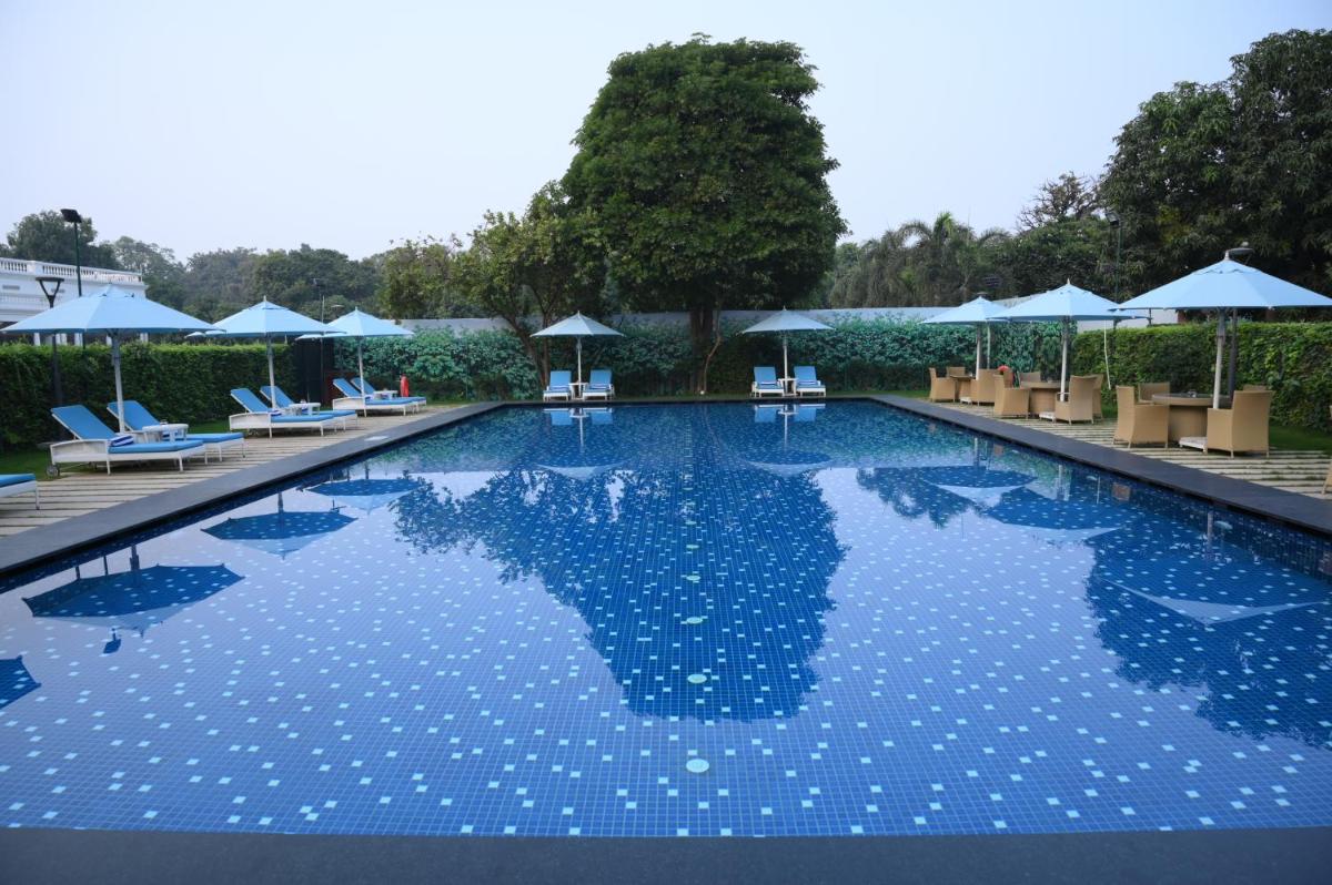 a large swimming pool with chairs and umbrellas at Taj Ganges Varanasi in Varanasi