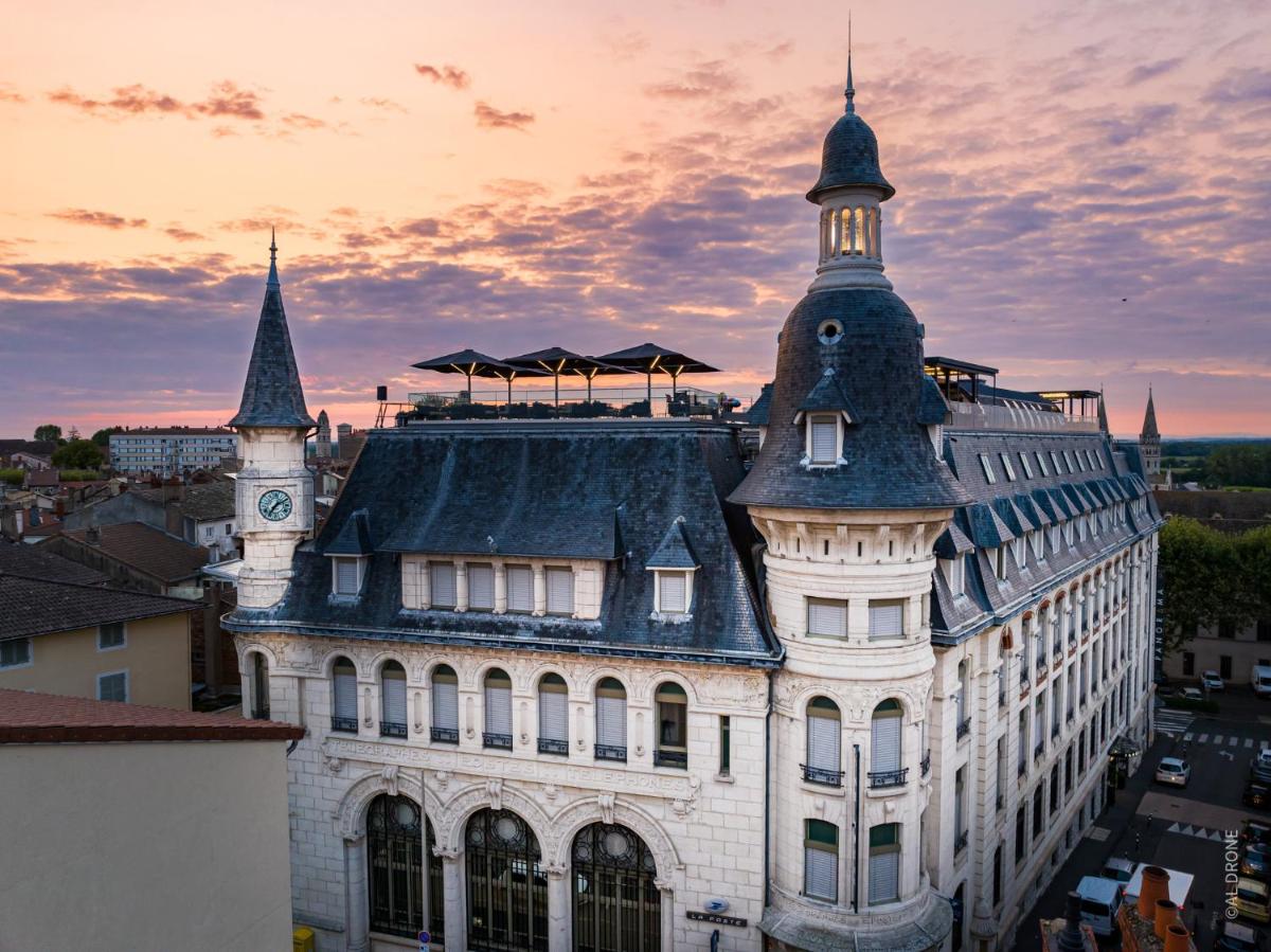un bâtiment avec une tour d'horloge au sommet dans l'établissement HÔTEL & SPA Panorama 360, à Mâcon