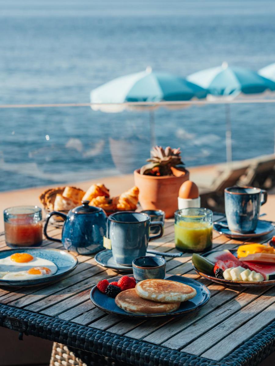 une table en bois avec de la nourriture pour le petit-déjeuner sur une plage dans l'établissement Tiara Miramar Beach Resort, à Théoule-sur-Mer