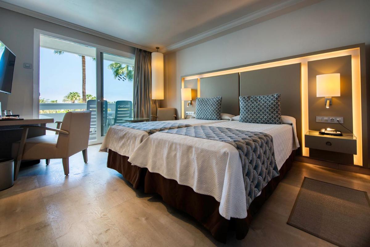 Una habitación de hotel con una cama grande y un escritorio. en Spring Hotel Vulcano, en Playa de las Américas