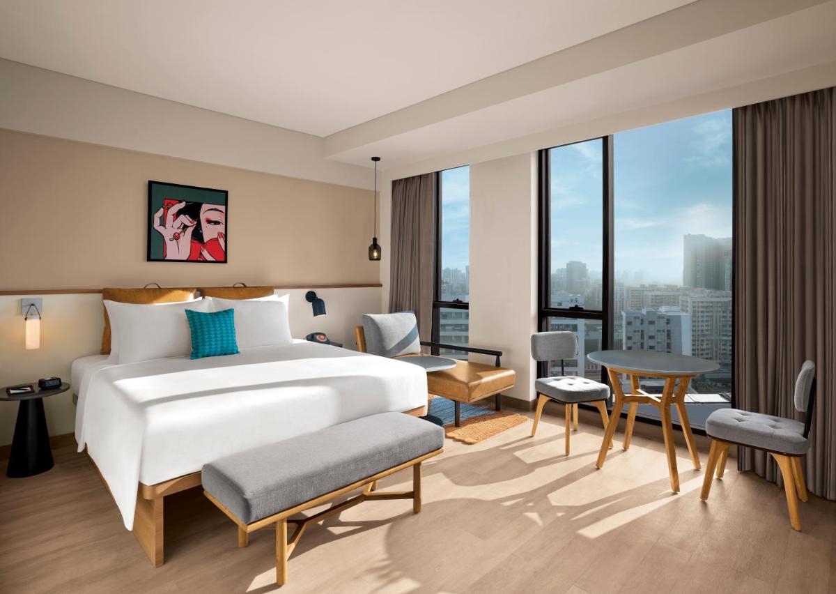 a hotel room with a bed and a large window at Moxy Mumbai Andheri West in Mumbai