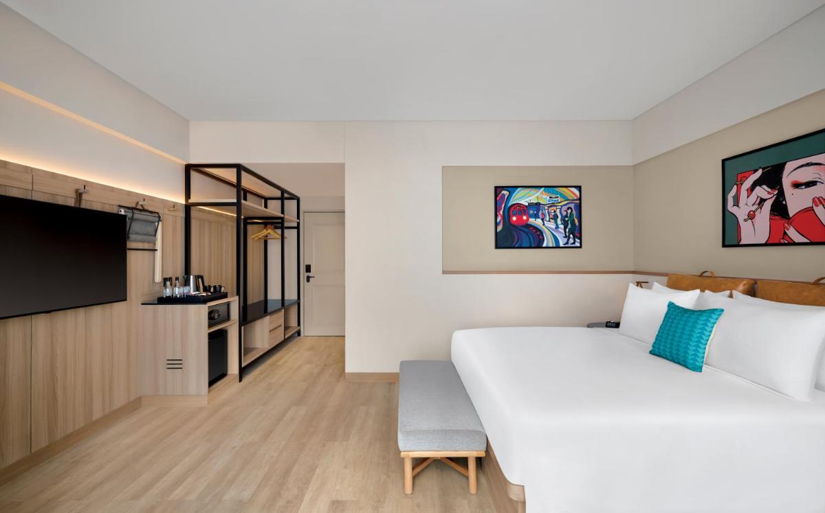 a bedroom with a large bed and a flat screen tv at Moxy Mumbai Andheri West in Mumbai