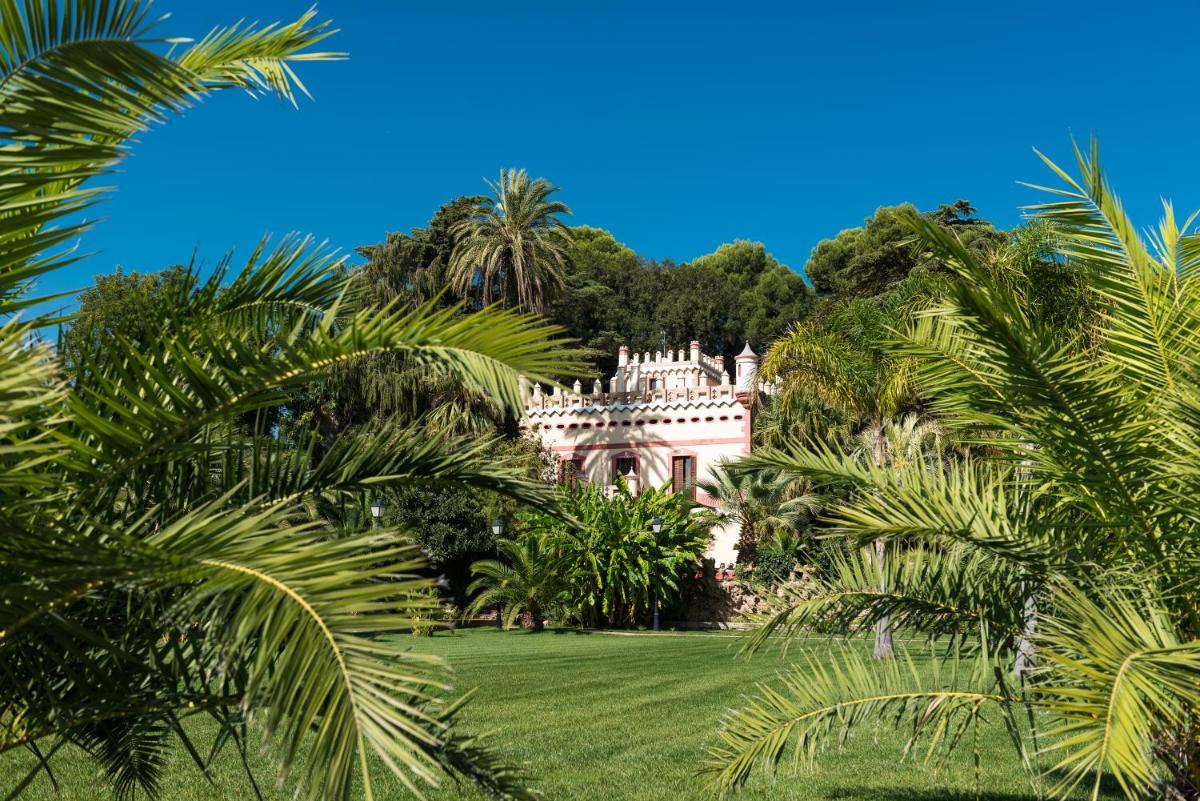 una antigua mansión rodeada de palmeras en un césped en Hotel Villa Retiro, en Xerta (Cherta)