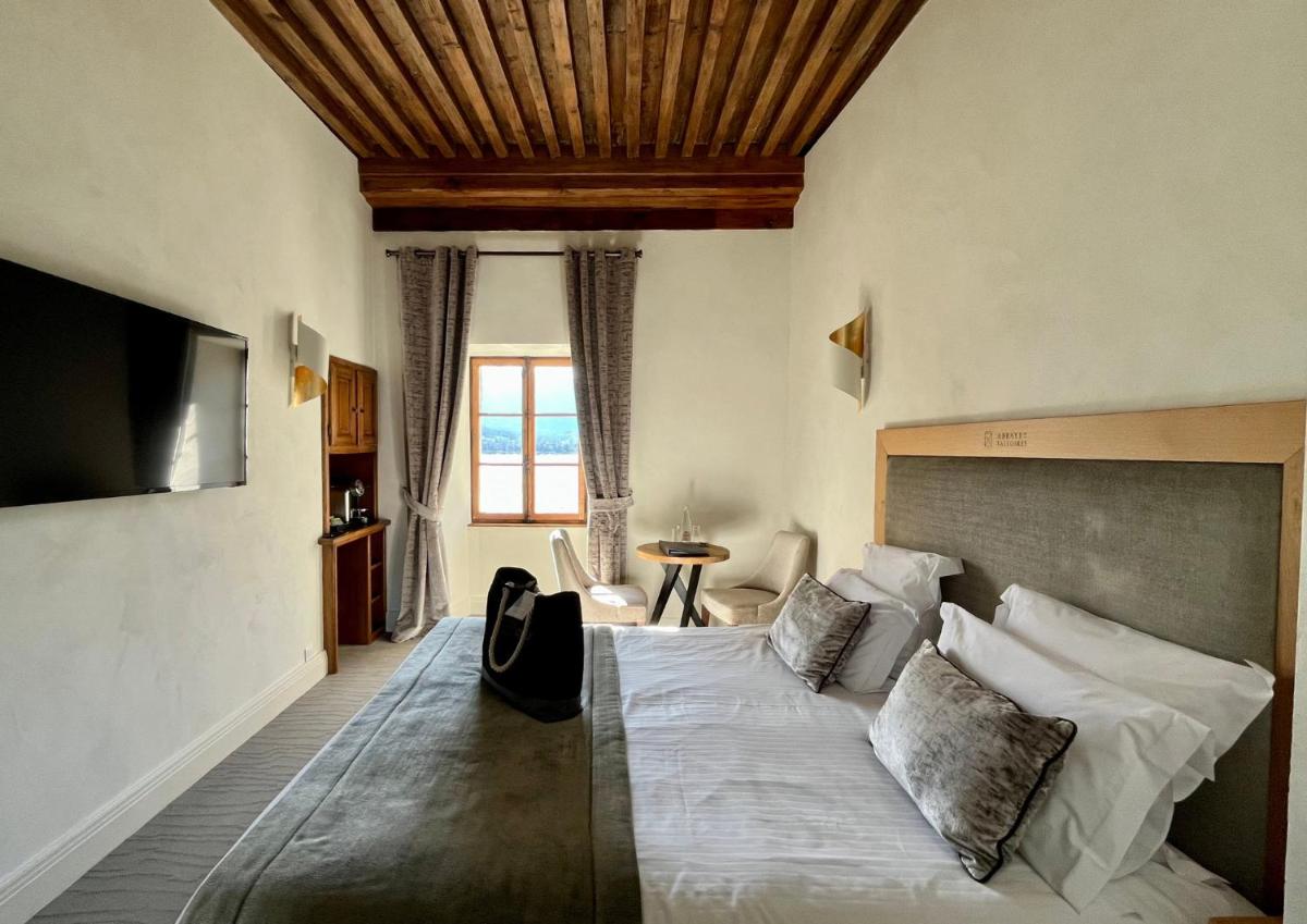 une chambre avec un grand lit et une table dans l'établissement Abbaye de Talloires, à Talloires