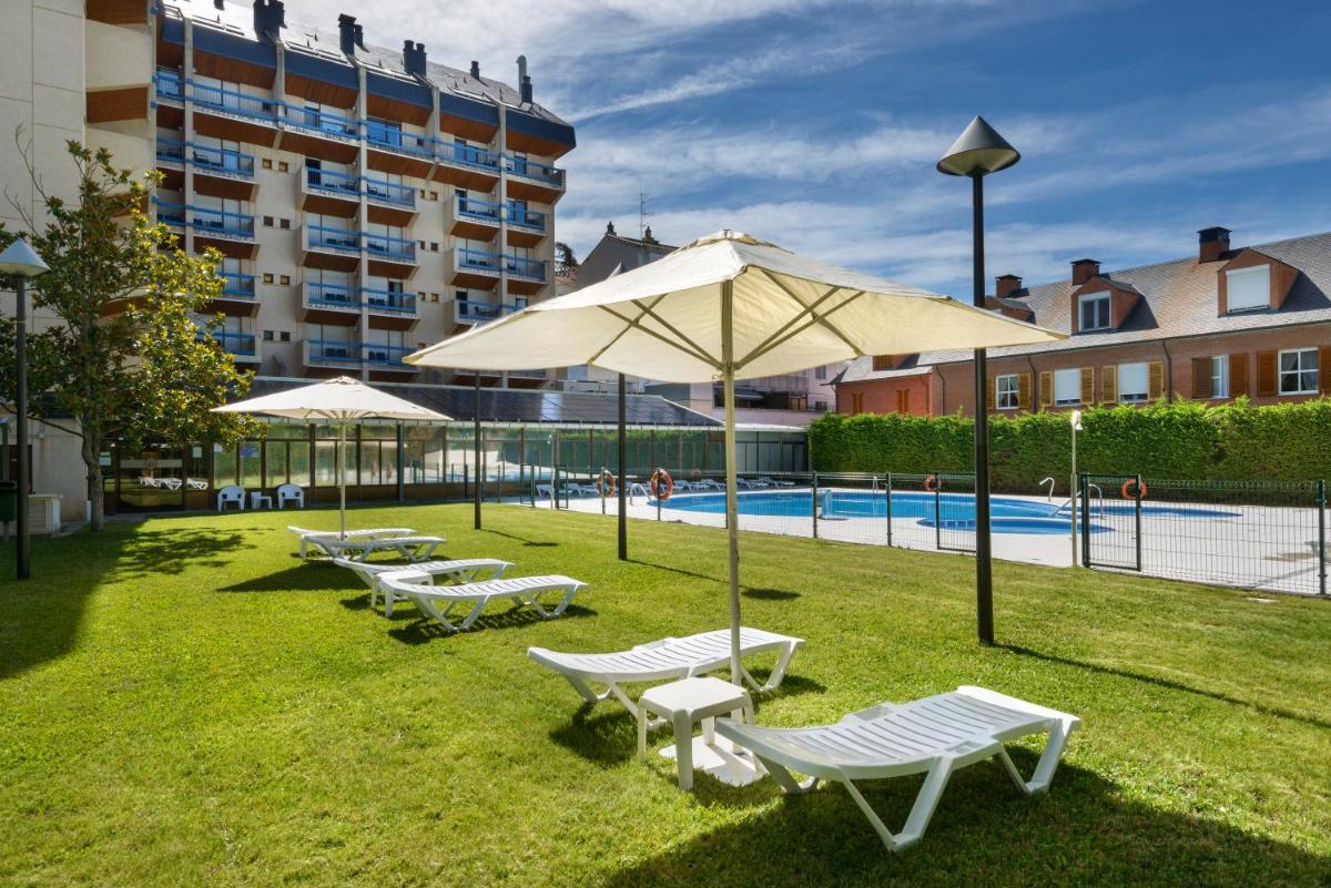 Un grupo de sillas y sombrillas junto a una piscina. en Oroel Hotel & SPA, en Jaca