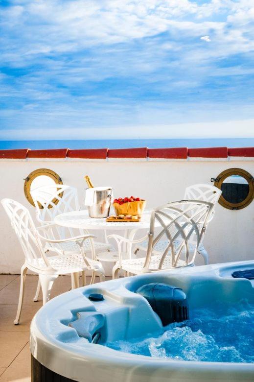 un patio avec une table et des chaises et un bain à remous dans l'établissement Grand Hotel Des Sablettes Plage, Curio Collection By Hilton, à La Seyne-sur-Mer