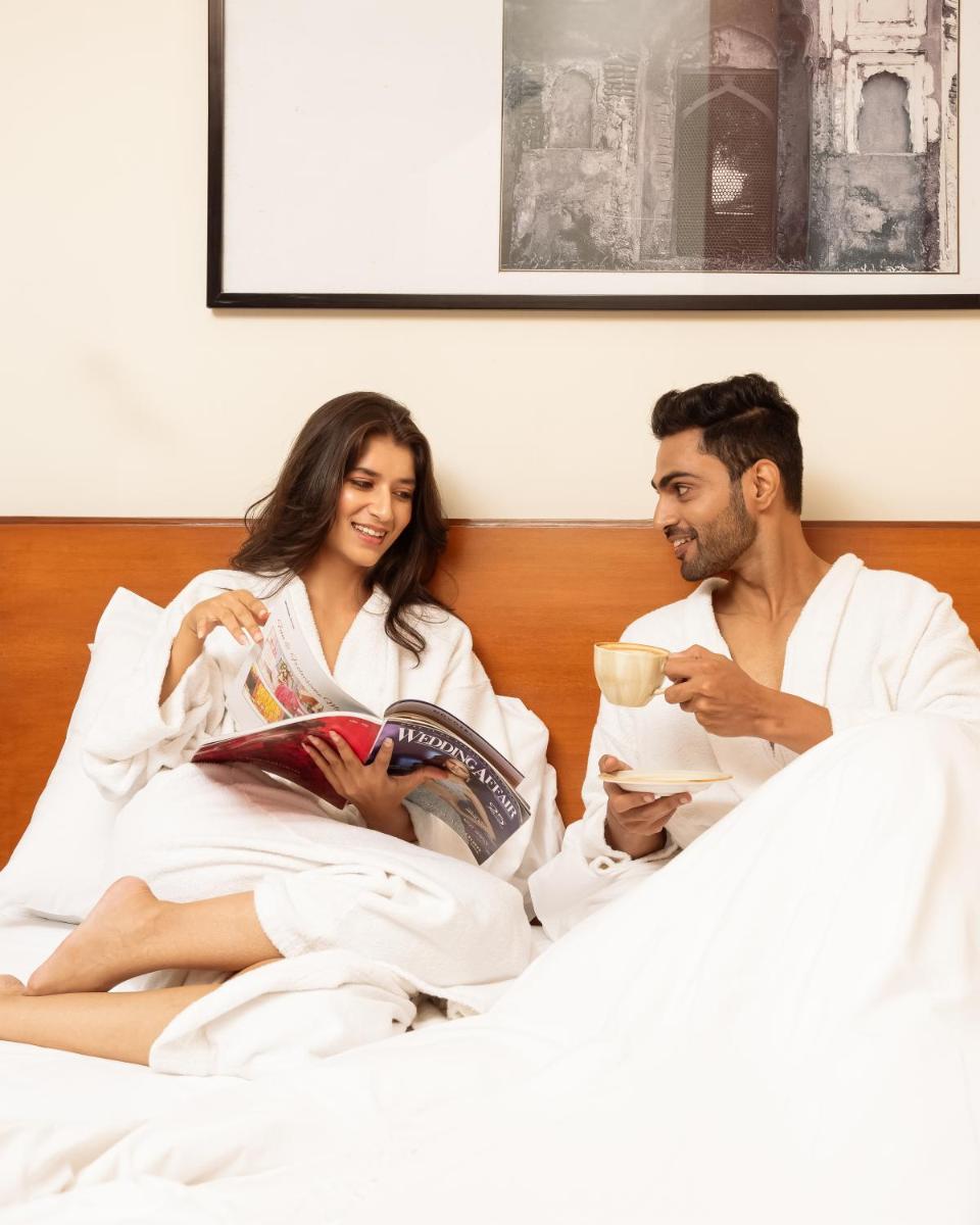 a man and woman sitting in bed reading books and drinking coffee at Hyatt Pune in Pune
