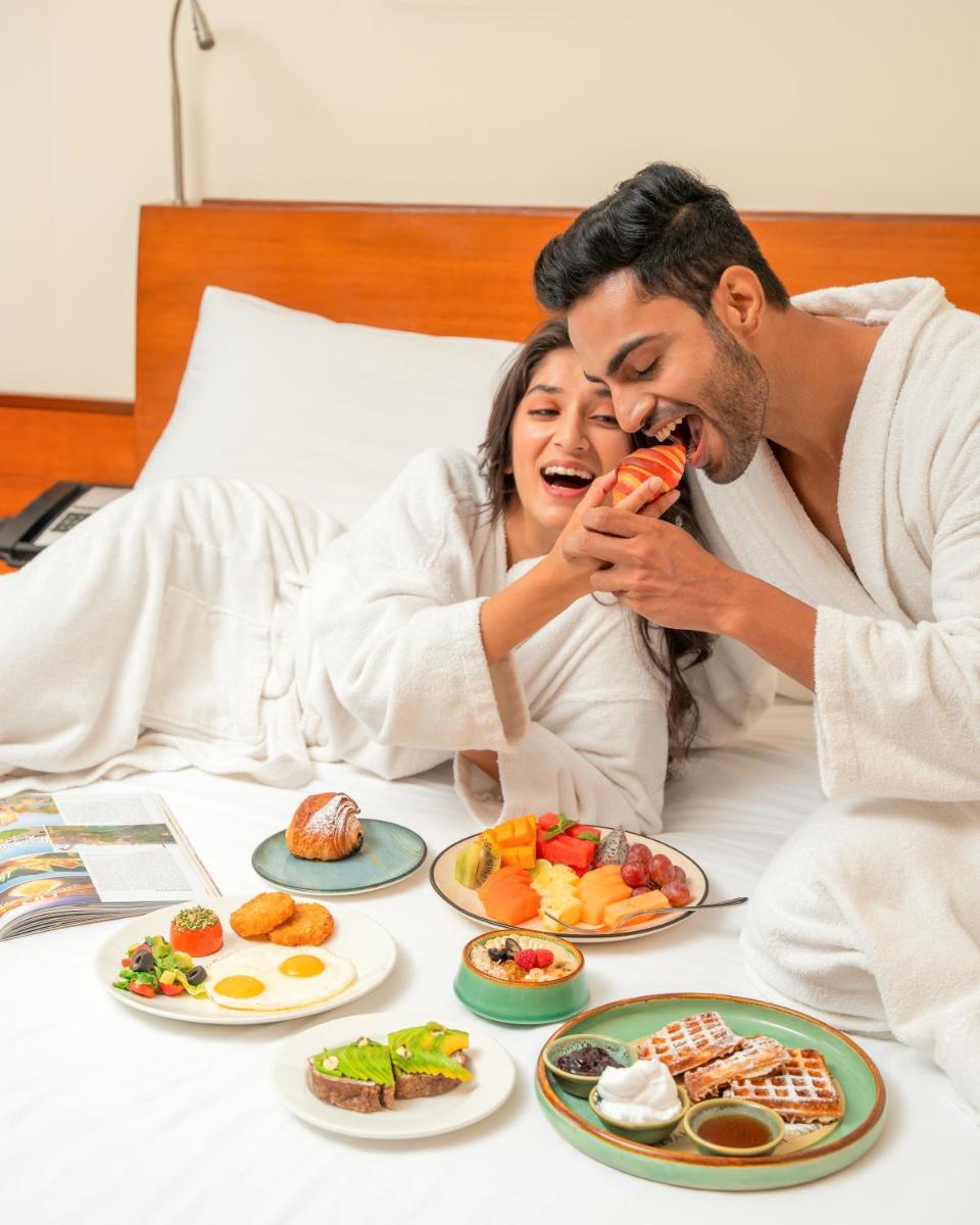 a man and a woman eating food in bed at Hyatt Pune in Pune