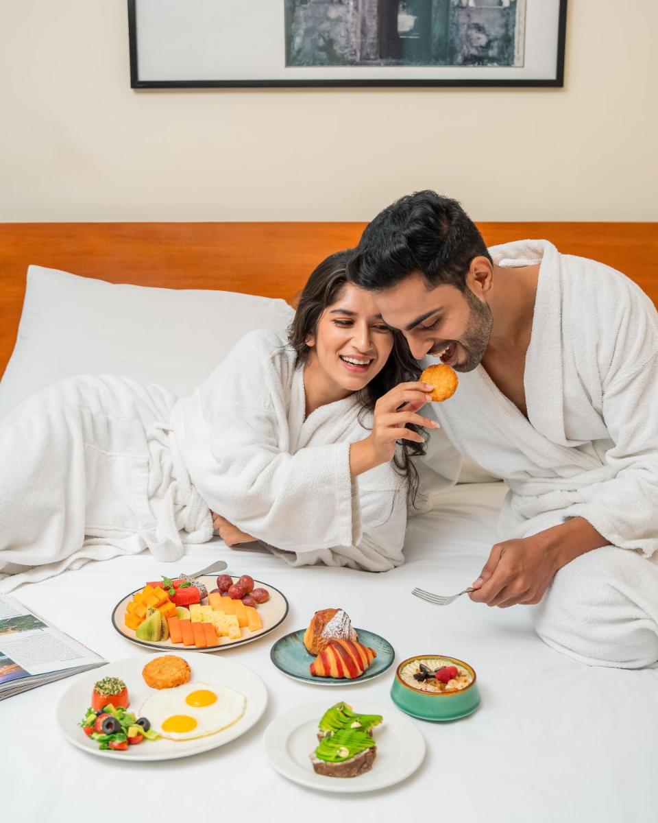 a man and a woman laying on a bed eating food at Hyatt Pune in Pune