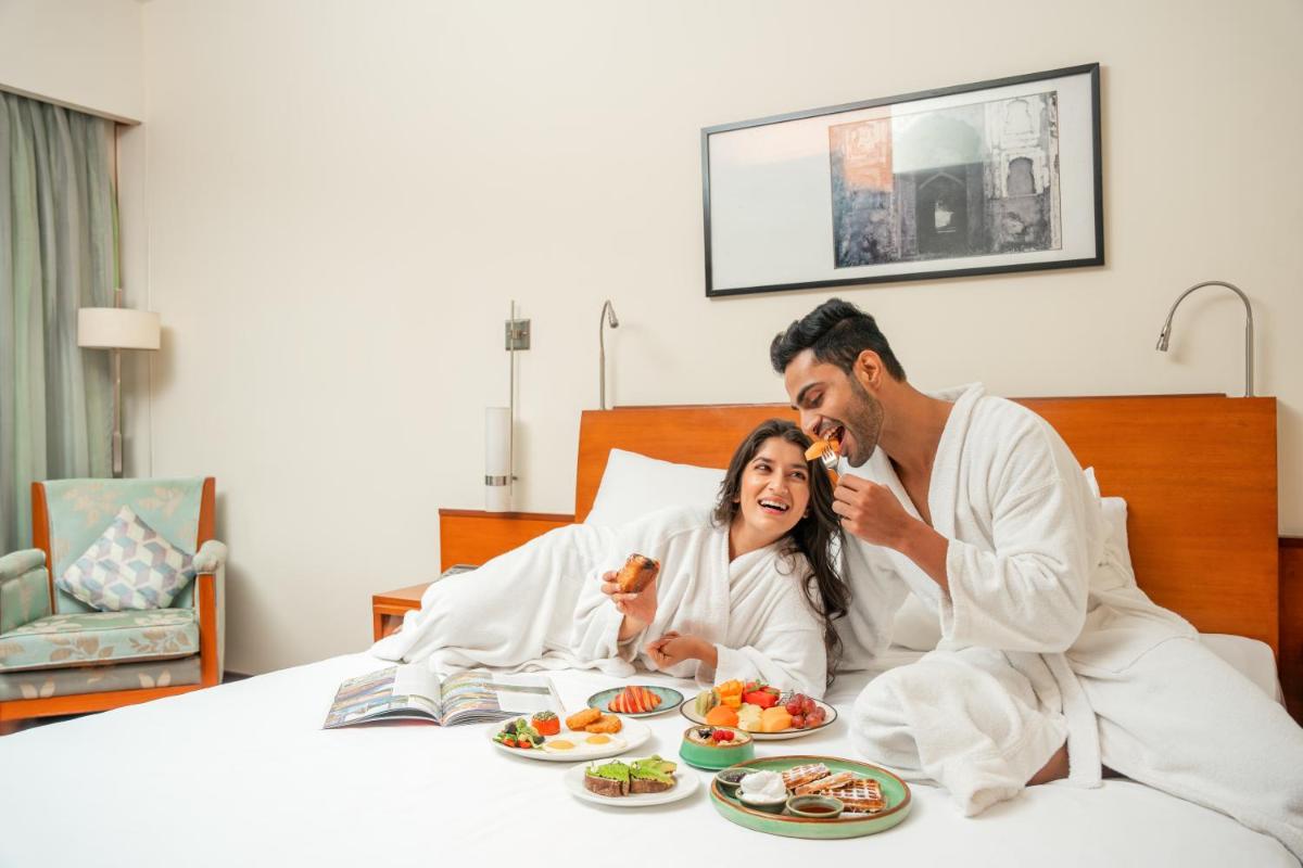 a man and woman in bed with plates of food at Hyatt Pune in Pune