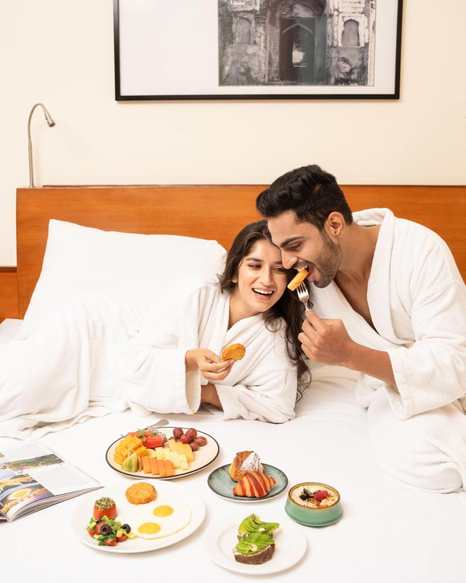 a man and a woman laying in bed eating food at Hyatt Pune in Pune
