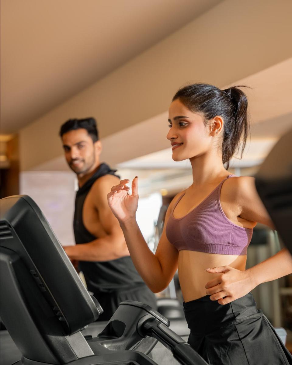 a man and woman running on a treadmill in a gym at Hyatt Pune in Pune