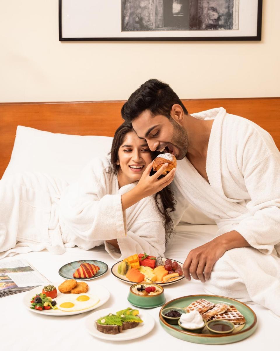 a man and woman laying in bed eating food at Hyatt Pune in Pune