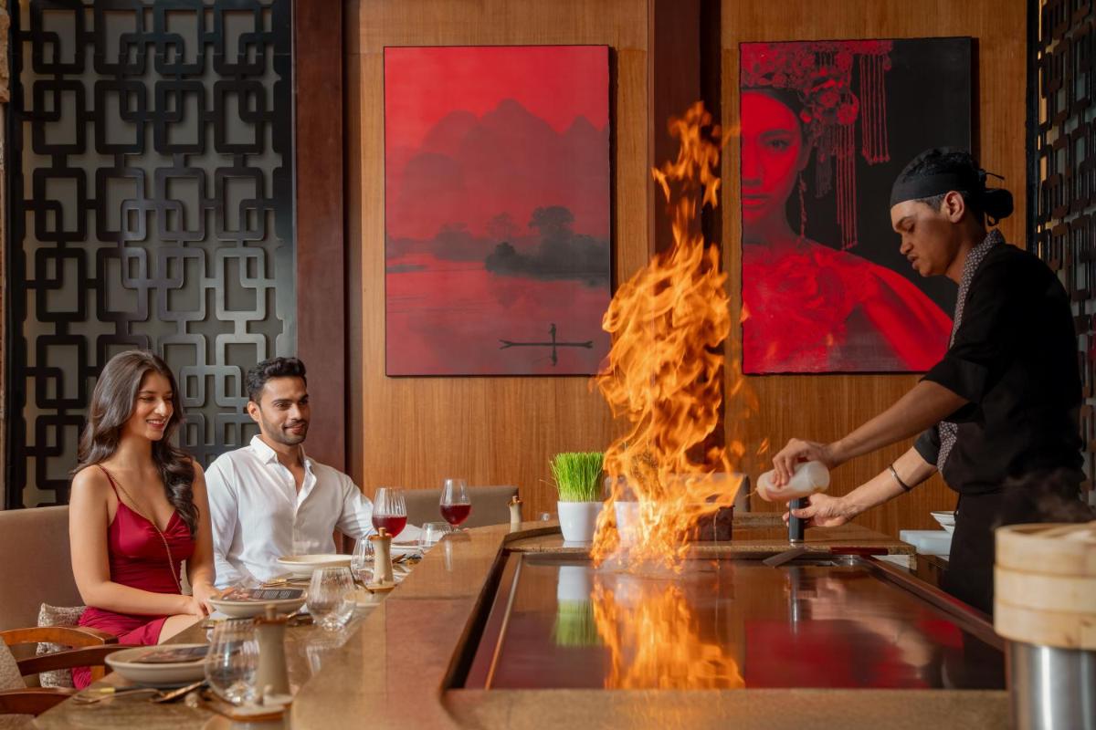 a man cooking food at a bar in a restaurant at Hyatt Pune in Pune