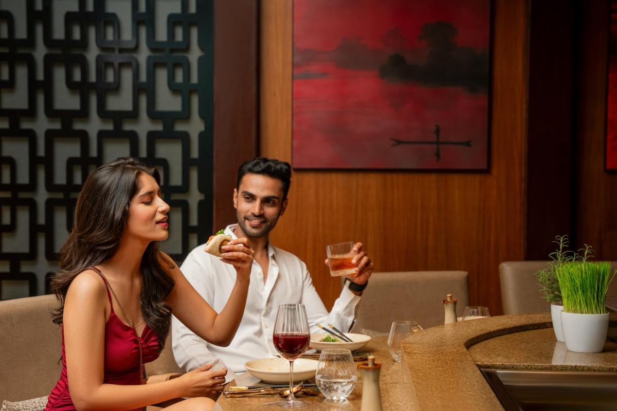 a man and woman sitting at a table with a glass of wine at Hyatt Pune in Pune